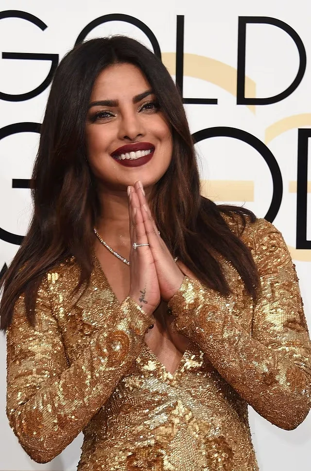 এই লুকের সঙ্গে ডিপ অক্সব্লাড লিপস্টিক যোগ করেছিল তীব্র কনট্রাস্ট। চুলে ছিল নরম ঢেউ, আর অ্যাকসেসরিজ ছিল সীমিত—যাতে পোশাকটাই হয়ে ওঠে আসল স্টেটমেন্ট।