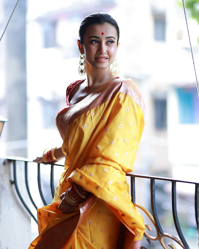 লাল পাড়ের হলুদ সিল্ক শাড়িতে সাবেকি ঢং ধরা পরছে। মিনিমাল সোনার গয়না, চুড়ি , লাল টিপ, আর আইলাইনার তাঁর সাজের অন্যতম আকর্ষণ