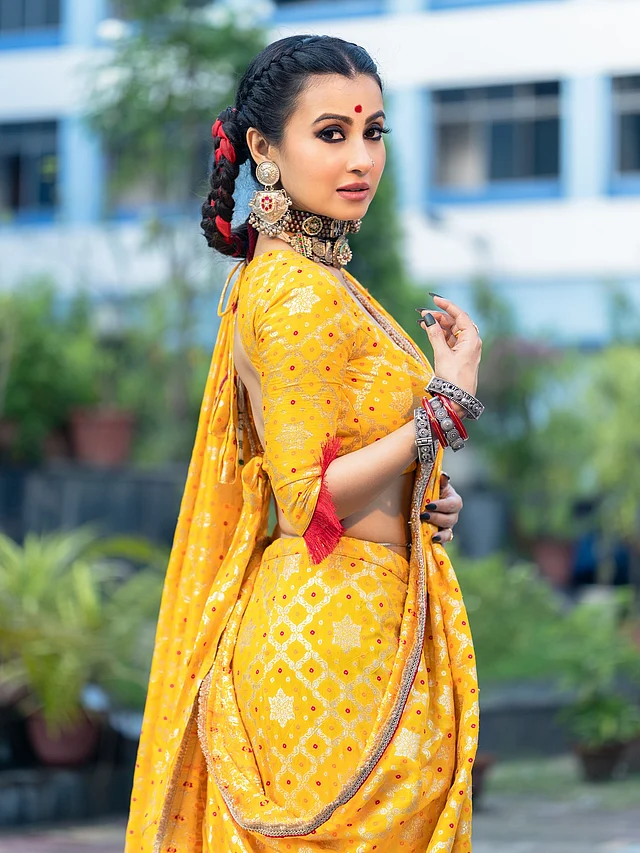 মনামী কিছুটা ভিন্নধর্মী বসন্তের সাজে ফ্রেমে ধরা দিয়েছেন। পরনের হলুদ শাড়িটি সোনালি-লাল মোটিফে সাজানো, ড্রেপিং পরিপাটি আর স্টাইলিশ। মিলিয়ে পরেছেন ব্যাকলেস ম্যাচিং ব্লাউজ। গলায় ভারী অক্সিডাইস চোকার নেকপিস, কানে বড় ঝুমকা আর হাতে চুড়ি পরেছেন সুন্দরী ।কাজল কালো চোখ, আবিরের অসম লাল টিপ, হাতে কালো নেইলপলিশ—সবকিছুই অন্যরকম । তবে সবচেয়ে ভিন্নত্ব এনেছে মাঝ সিঁথি করে বেণী করা চুলে লাল ফিতা জড়ানো স্টাইলটি ।