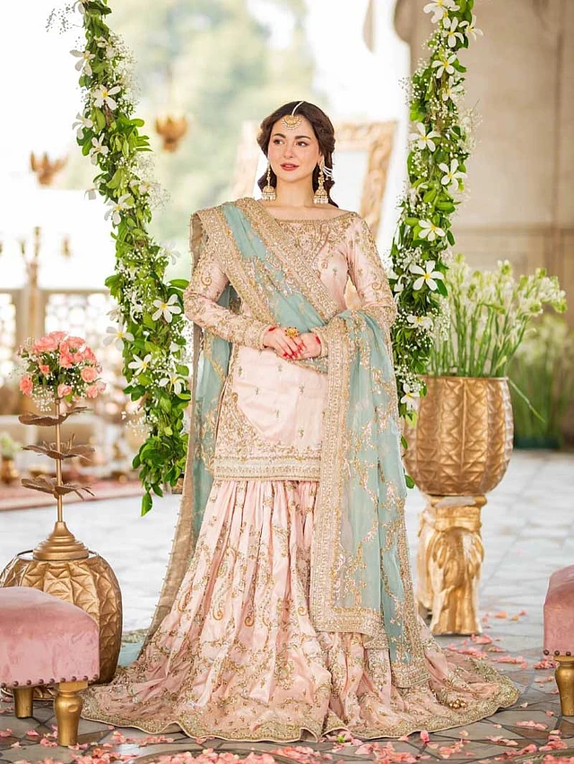 প্যাস্টেল শেডের ব্রাইডাল গারারার সঙ্গে টানা দেওয়া ঝুমকা আর টিকলি পরেছেন হানিয়া। মেহেদি রাঙা হাত নজর কাড়ছে