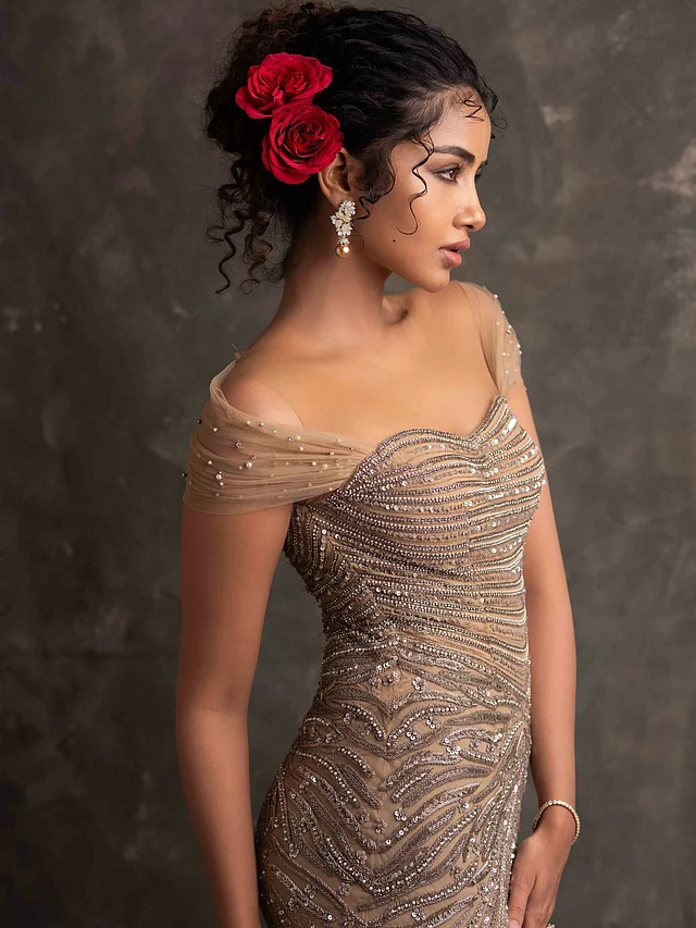 এরসঙ্গে পার্ল ড্রপ ফ্লোরাল ইয়াররিং, আপডো কোঁকড়ানো চুলে লাল গোলাপে গোল্ড আউটফিটের সঙ্গে উজ্জ্বল কনট্রাস্ট এনেছে ।