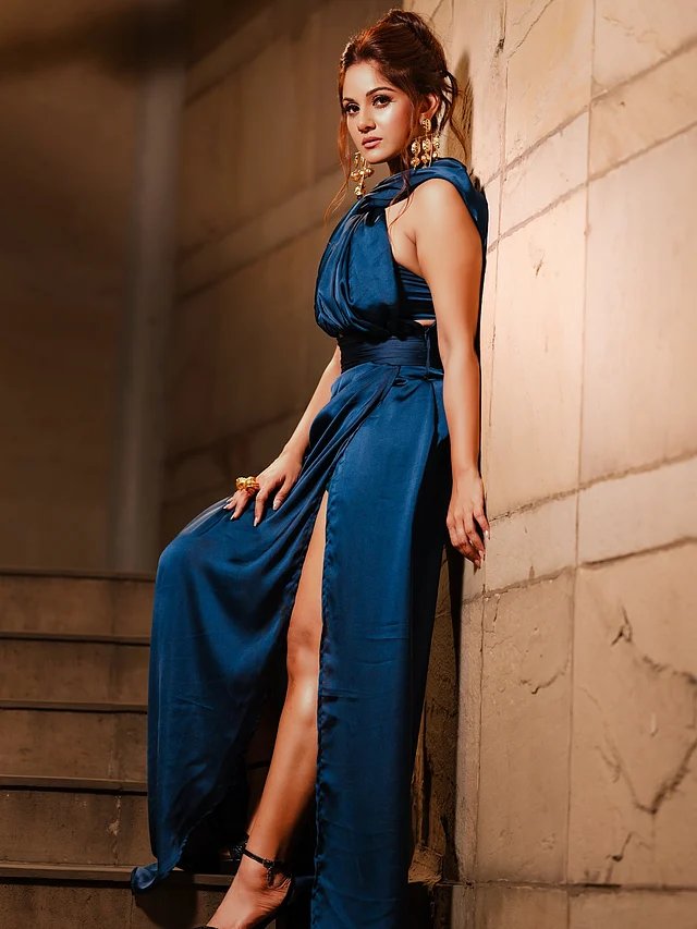 এখানে তিনি পরেছেন নীল স্যাটিনের থাই স্লিট হলটারনেক গাউন