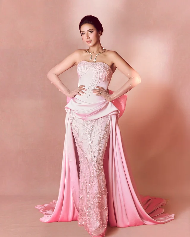 স্ট্র্যাপলেস মারমেইড কাটের গাউনে গ্যাদার্ড ফেব্রিক দিয়ে এক্সটেনশন অনেকটা ট্রেনের মতো নেমে গিয়েছে দুই দিকে।