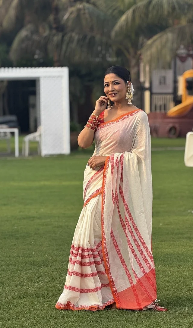 বাঁধন পরেছেন সাদা রঙের একটি শাড়ি, যার পাড়ে রয়েছে লাল ও কমলা ফ্লোরাল নকশা। এই রঙের সংমিশ্রণ বাঙালির ঐতিহ্যবাহী বৈশাখী সাজের প্রতীক।