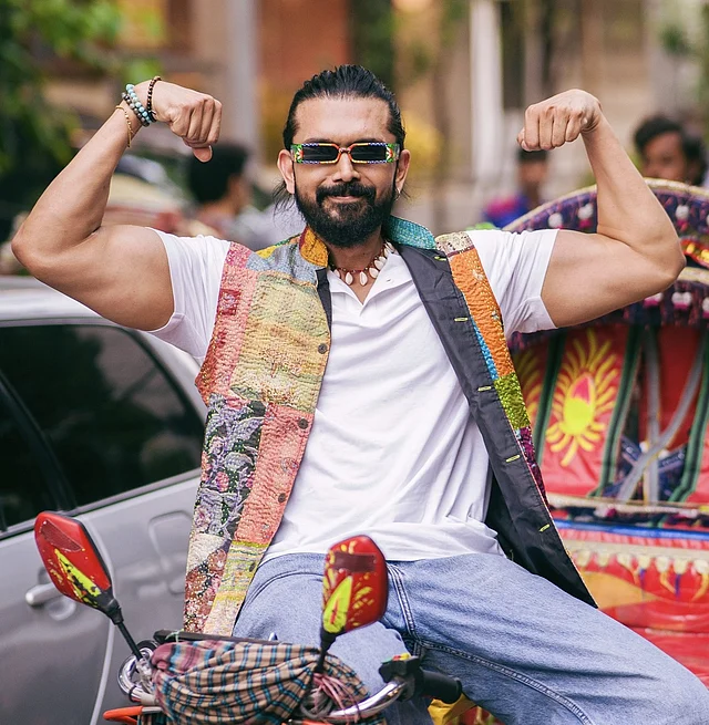 প্যাচওয়ার্কের কোটি, সাদা শার্ট, জিন্স, হাতে ব্রেসলেট আর চোখের স্টাইলিশ শেডসে নিজের বাইসেপ ফ্লন্ট করছেন আরিফিন শুভ। তাও রিকশাচালকের আসনে ম্যাচো মুডে।