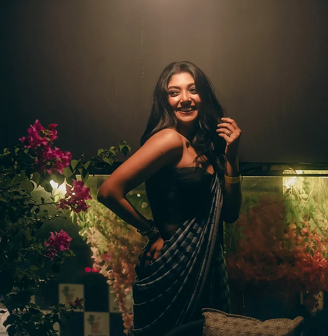 রাতের মৃদু আলোয় বাগানবিলাসের পাশে ধূসর-কালো চেকের শাড়ি আর স্ট্র্যাপলেস ব্লাউজে দেবলীনা