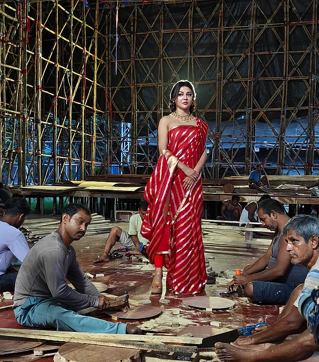 প্যান্ডেল তৈরির ব্যস্ততার মাঝে জয়ার টকটকে লাল শাড়ি সহজেই নজর কাড়ে। উৎসবের আবহে রঙের উজ্জ্বলতা যেন বাড়িয়ে দিয়েছে ছবির আবেদন।