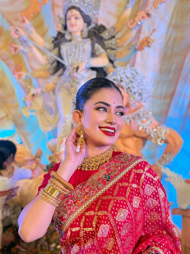 সোনার চোকার, বড় ঝুমকো ও মোটা বালার সঙ্গে মসৃণ খোঁপায় ফুলের ছোঁয়া সাজটিকে করেছে আরও আকর্ষণীয়।