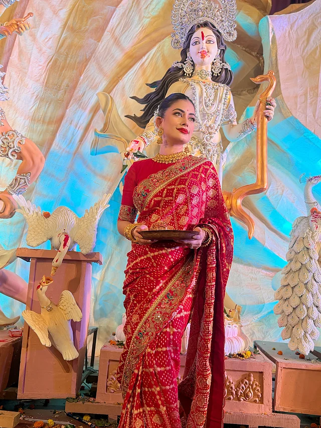 ফুলের মোটিফ, সোনালি জরি এবং আঁচল ও পাড়ের ময়ূরের নকশার এমব্রয়ডারি শাড়িটিকে দিয়েছে রাজকীয় আবহ। সঙ্গে লাল ব্লাউজে বজায় রয়েছে রঙের সামঞ্জস্য।