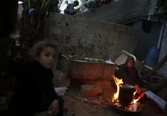 A Palestinian woman burns firewood to cook at her house in the northern Gaza Strip on 20 March 2014. Photo: Reuters