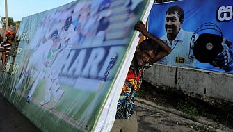 Sri Lankan workers carry a billboard bearing the image of Sri Lanka cricketer Mahela Jayawardene at the Galle International Cricket Stadium in Galle on August 3, 2014. AFP