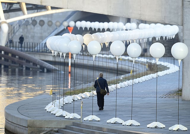 A man walks past a row of lanterns that are part of the light installation Lichtgrenze (Light border) on the course of the former Berlin wall near the Reichstag building in Berlin on November 7, 2014. Photo: AFP