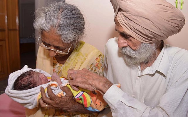 Indian parents Mohinder Singh Gill ®, 79, and Daljinder Kaur, 70, hold their newborn baby boy Arman at their home in Amritsar. Photo: AFP