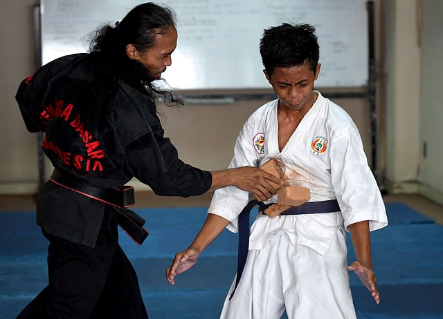 This picture taken on 2 October, 2016 shows a teenaged student (R) standing his ground as he takes a blow from a brick being smashed onto his stomach during a demonstration of his `pencak silat` martial arts skills in Jakarta. Photo: AFP
