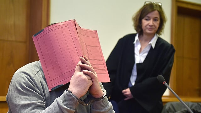 German former male nurse Niels H hiding his face behind a folder as he waits next to his lawyer Ulrike Baumann ® for the opening of another session of his trial. AFP file photo