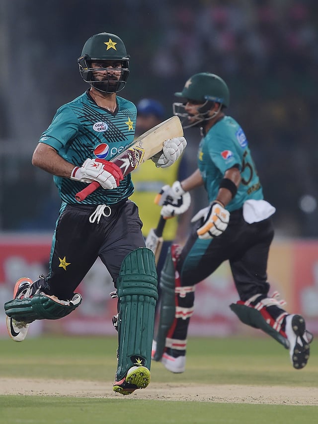 Pakistani batsmen Ahmed Shahzad (L) and Babar Zaman run between the wickets during the first Twenty20 international match between the World XI and Pakistan at the Gaddafi Cricket Stadium in Lahore on 12 September, 2017. Photo: AFP