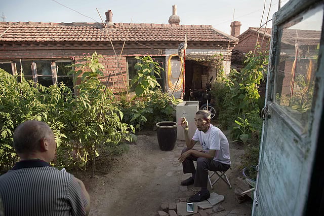 Farmer Wang Enlin ® sits in his garden at his house in Yushutun. Wang Enlin, an elderly farmer who left school when he was 10 years old and taught himself law armed with a single textbook and dictionary, makes for an unlikely eco-warrior. AFP file photo