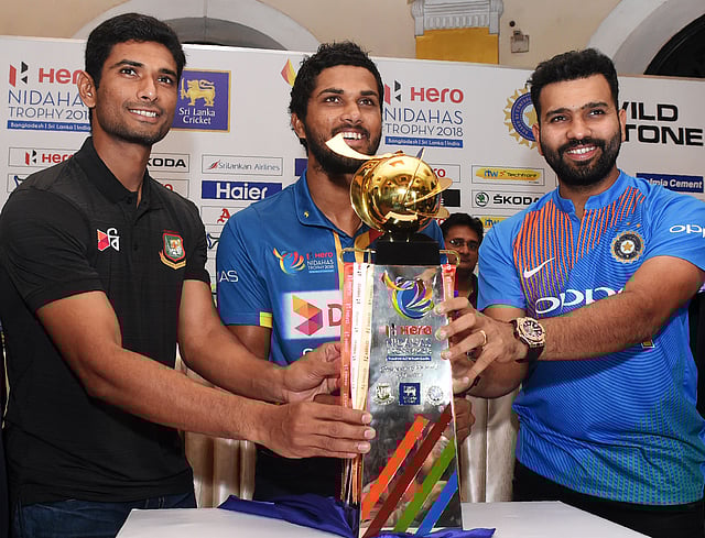 Cricket captains Dinesh Chandimal (C) of Sri Lanka, Rohit Sharma (R) of India and Mahmudullah Riyad (L) of Bangladesh pose behind the Nidahas tri-nation Twenty20 tournament series trophy during a press conference in Colombo on March 5, 2018. The Nidahas Trophy tri-nation Twenty20 tournament involving Sri Lanka, Bangladesh and India starts in Colombo on 6 March 2018. AFP