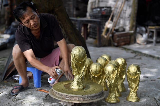 This picture taken on 5 June, 2018 shows Vietnamese craftsman Vuong Hong Nhat spraying gold colour paint on a plaster model of the football World Cup trophy at a workshop in Hanoi. Photo: AFP