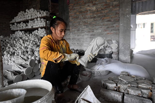 This picture taken on 5 June, 2018 shows a Vietnamese worker making a plaster model of the football World Cup trophy at a workshop in Hanoi. Photo: AFP
