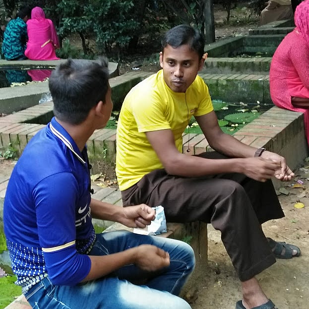 Two visitors sitting by the lily pond eating peanuts and strewing the shells all over. Many throw these into the water.