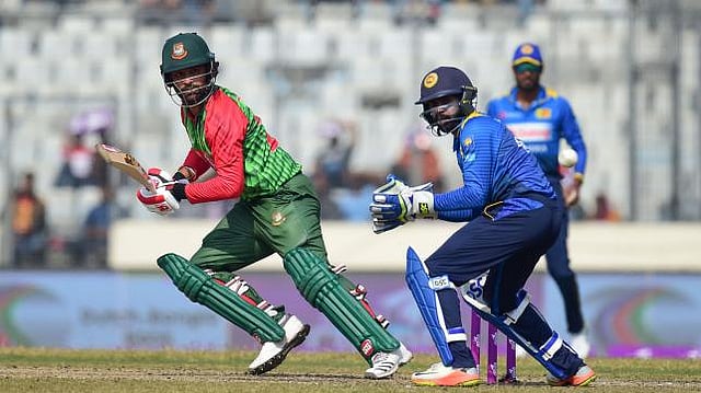 Tamim Iqbal (L) plays a shot as the Sri Lanka wicketkeeper Niroshan Dickwella (C) looks on during the third one day international (ODI) cricket match of the Tri-Nations Series between Bangladesh and Sri Lanka at the Sher-e-Bangla National Cricket Stadium in Dhaka on 19 January 2018. AFP