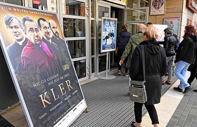 People pass by poster of movie “Kler” (The Clergy) at the entrance the cinema in Warsaw on 29 September. Photo: AFP