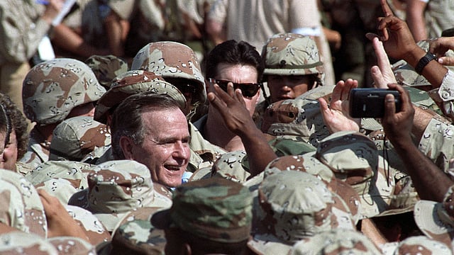 US president George HW Bush is surrounded by US military personnel as he greets troops following an arrival ceremony in the eastern Saudi Arabian city of Dhahran on 22 November 1990. Reuters File Photo