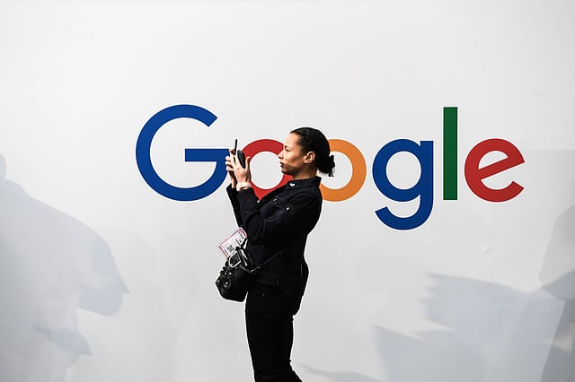 a woman takes a picture with two smartphones in front of the logo of the US multinational technology and Internet-related services company Google as he visits the Vivatech startups and innovation fair, in Paris. Photo: AFP