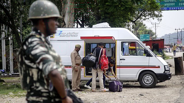 An Indian security forces personnel stands guard as Jammu Kashmir police men check the luggage and vehicles of commuters on the Jammu-Srinagar National highway at Nagrota some 25 kms from Jammu on 2 August, 2019. Photo: AFP