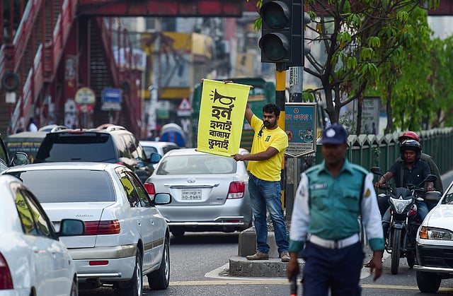 In this photo taken on 22 March 2019, Mominur Rahman Royal holds a banner with a Bengali slogan -- `Horn hudai, Bajay Bhudai` that translates to `only the idiot honks horn unnecessarily` -- on a busy street in Dhaka. Photo: AFP