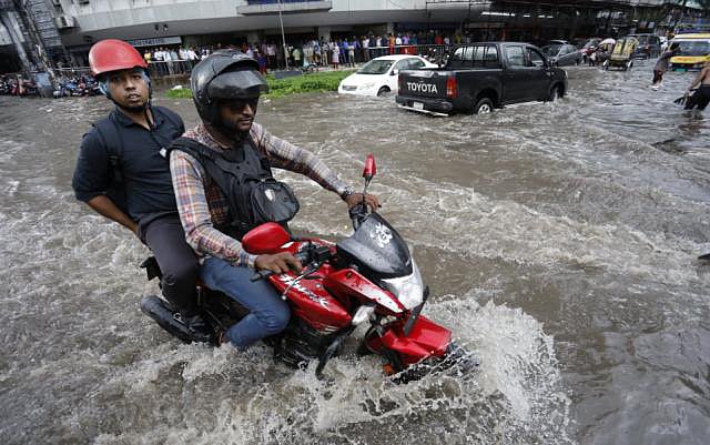 A biker drives through rain water in Karwan Bazar area in Dhaka. Photo: Dipu Malakar