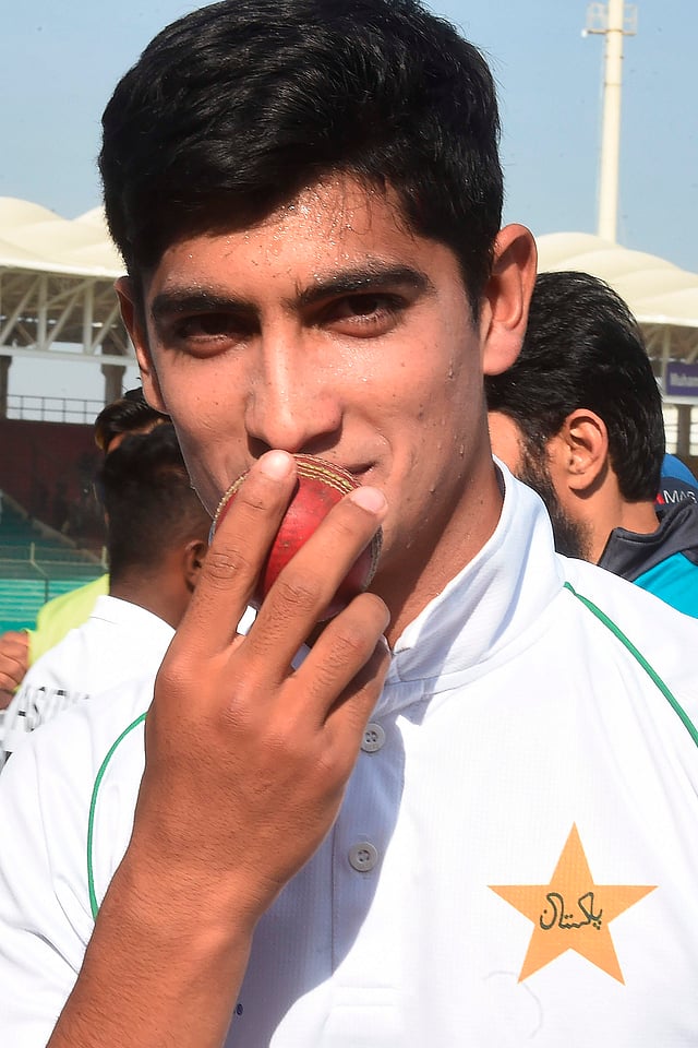 Pakistan`s Naseem Shah poses for a photograph as he kisses a ball for taking five wickets after winning the second Test cricket match between Pakistan and Sri Lanka at the National Cricket Stadium in Karachi on 23 December, 2019. Photo: AFP