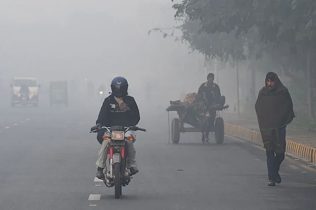 In this picture taken on 6 December 2019, commuters make their way along a street amid heavy smog conditions in Lahore. Photo: AFP