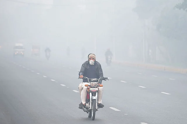 In this picture taken on 6 December 2019, commuters ride on a street amid heavy smog conditions in Lahore. Photo: AFP
