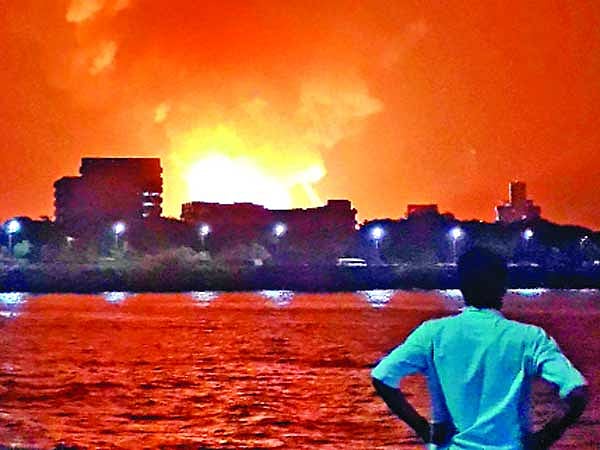 মুম্বাইয়ে নৌবাহিনীর ডকইয়ার্ডে জ্বলছে আইএনএস সিন্ধুরক্ষক। দূরে দাঁড়িয়ে এক ব্যক্তি তা দেখছেন ষ ছবি: রয়টার্স