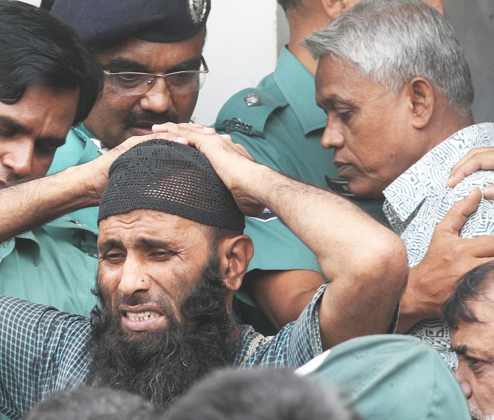 পিলখানা হত্যা মামলার রায়ে ফাঁসির দণ্ডপ্রাপ্ত ডিএডি তৌহিদকে (ডানে সাদা জামা) আদালত থেকে কারাগারে নিয়ে যাওয়া হচ্ছে—ছবি: মনিরুল আলম