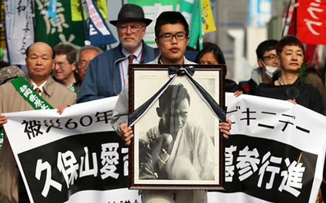 ইয়াইজু বন্দরের কাছে শোক সমাবেশে জাপানি জাহাজের প্রধান বেতার প্রকৌশলী আইকিচি কুবোয়ামার প্রতিকৃতি বহন করছে সমবেতরা। ছবি: এএফপি