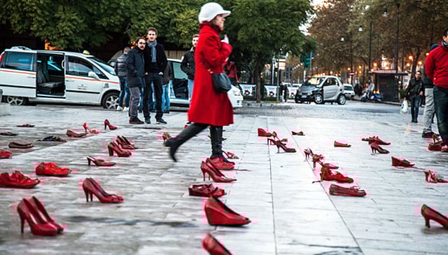 নারীর প্রতি সহিংসতার বিরুদ্ধে সচেতনতা গড়তে ইতালির পালের্মো শহরের রাজপথে এভাবেই রেখে দেওয়া হয়েছিল শত জোড়া লাল জুতা। পথচারীরা পড়ে থাকা জুতার মাঝ দিয়ে হেঁটে যাবেন আর বিষয়টি নিয়ে ভাববেন। এটাই শিল্পীর চাওয়া। ছবি: দ্য গার্ডিয়ান