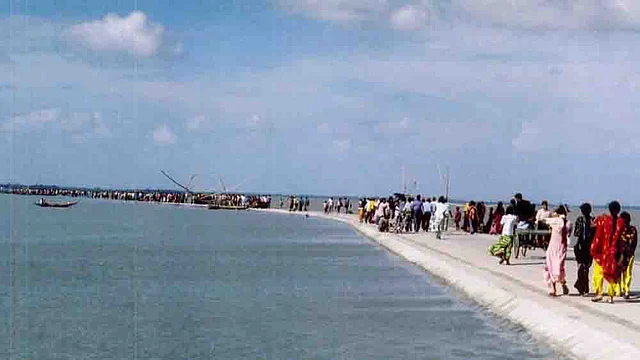 বিস্তীর্ণ জলরাশির মাঝে নির্মাণ করা সড়ক দিয়ে দল বেঁধে ছুটছে ঈদের ছুটিতে আসা লোকজন। ছবিটি শুক্রবার (০১ আগস্ট ২০১৪) সকালে তোলা। ছবি: মুক্তার হোসেন, নাটোর