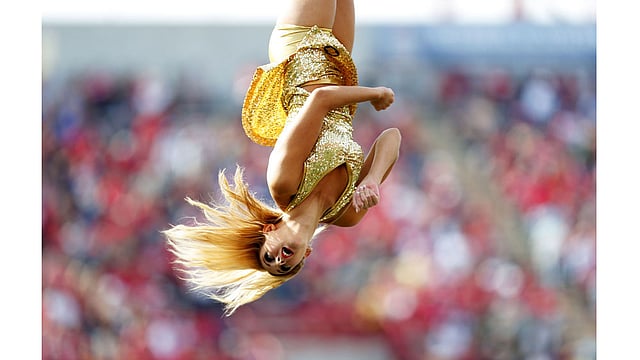 কানাডার আলবার্টায় সোমবার সিএফএল ফুটবল গেম চলাকালে শূন্যে লাফিয়ে ডিগবাজি খান এক চিয়ারলিডার। ছবি: এএফপি