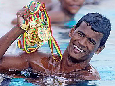 পদকগুলো যেন পদ্ম ফুল হয়ে ফুটে আছে হাতে। ১৩টি সোনা জিতে বয়সভিত্তিক সাঁতারে এবারও ছেলেদের সেরা বিকেএসপির আরিফুল। তাঁর সংগ্রহে ১০টি সোনা। কাল মিরপুর সুইমিং পুলে l প্রথম আলো