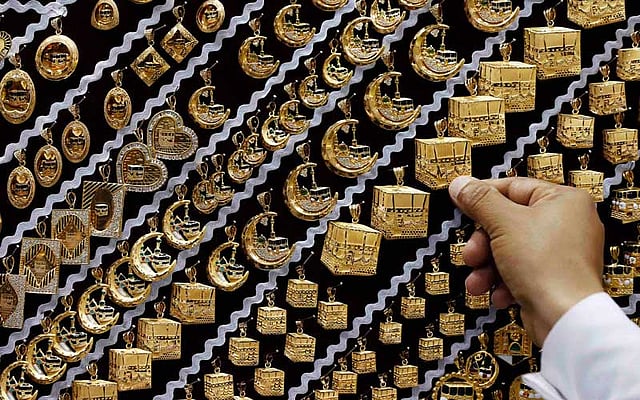 পবিত্র কাবা শরিফের নকশা ঠাঁই পেয়েছে স্বর্ণ দিয়ে বানানো লকেটে। হজ করতে যাওয়া হজযাত্রীদের অনেকেই সেগুলো নেড়েচেড়ে দেখছেন, দামে মিললে অনেকে কিনেও নিচ্ছেন। ছবিটি সৌদি আরব থেকে গতকাল শনিবার তোলা। ছবি: রয়টার্স