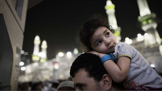 বাবা এসেছেন হজ পালনে। সঙ্গে আদরের বুড়িটিও। মক্কায় মঙ্গলবার কাবাঘরের মসজিদে নামাজ আদায়ের পর মুগ্ধচোখে ধর্মপ্রাণ হাজিদের আনাগোনা ​দেখতে দেখতে যাচ্ছে সে। ছবি: এএফপি