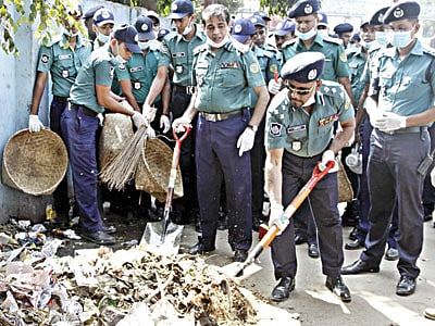 চট্টগ্রাম নগরের দামপাড়া এলাকায় রাস্তায় ফেলে রাখা ময়লা বেলচা দিয়ে সরিয়ে নিচ্ছেন নগর পুলিশ কমিশনার আবদুল জলিল মণ্ডল (ডানে)। সঙ্গে আছেন পুলিশের অন্য সদস্যরাও। ছবিটি গতকাল বেলা ১১টায় তোলা l প্রথম আলো