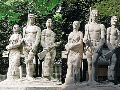 ঢাকা বিশ্ববিদ্যালয়ের কলা ভবনের সামনে মুক্তিযুদ্ধের চেতনার অন্যতম প্রতীক ‘অপরাজেয় বাংলা’ (বাঁয়ে)। ভাস্কর্যটিতে ফাটল দেখা দেওয়ায় সম্প্রতি এর সংস্কার করা হয়েছে। তবে সংস্কারের পর এর বৈশিষ্ট্যে কিছুটা পরিবর্তন এসেছে এবং সাদা দেখাচ্ছে (ডানে)। শিল্প সমালোচকেরা বলছেন, এতে ভাস্কর্যটির নান্দনিক ক্ষতি হয়েছে l ছবি: প্রথম আলো