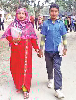 ছেলেকে নিয়ে স্কুল থেকে বাড়ি ফিরছেন রোজিনা খাতুন। রাজশাহীর বাগমারার গণিপুর ইউনিয়নের চান্দেরআড়া উচ্চবিদ্যালয়ের সামনে থেকে তোলা ছবি l প্রথম আলো