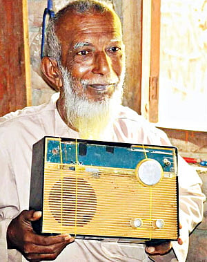 পাবনার ঈশ্বরদীর রূপপুর গ্রামের বাড়িতে থ্রি ব্যান্ডের ফিলিপস রেডিওটি হাতে কাশেম মোল্লা l ফাইল ছবি
