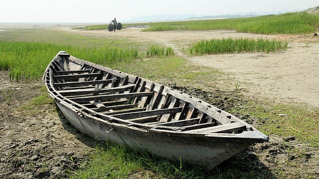 নদীর তট শুকিয়ে খটখট। নৌকা পড়ে আছে একলা। ছবি: সোয়েল রানা, বগুড়া
