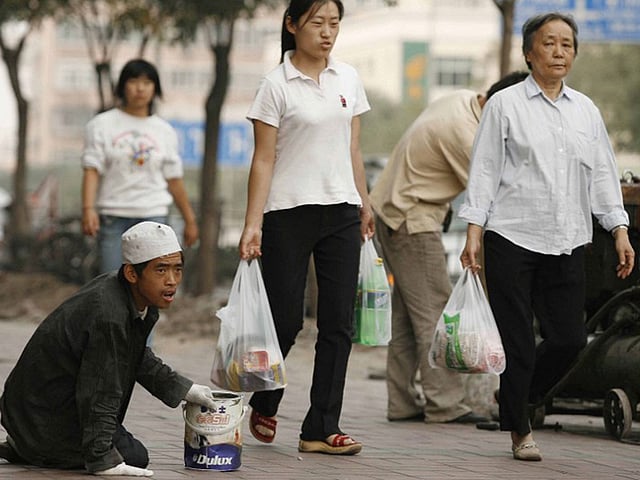 চীনে বেইজিংয়ের রাস্তায় বসে ভিক্ষাবৃত্তি করছেন উইঘুর সম্প্রদায়ের একজন যুবক। ছবি: এএফপি